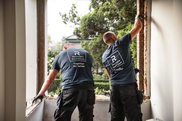 Két Reynaers Aluminium szerelő a régi ablakok szétszerelését végzi a helyszínen.