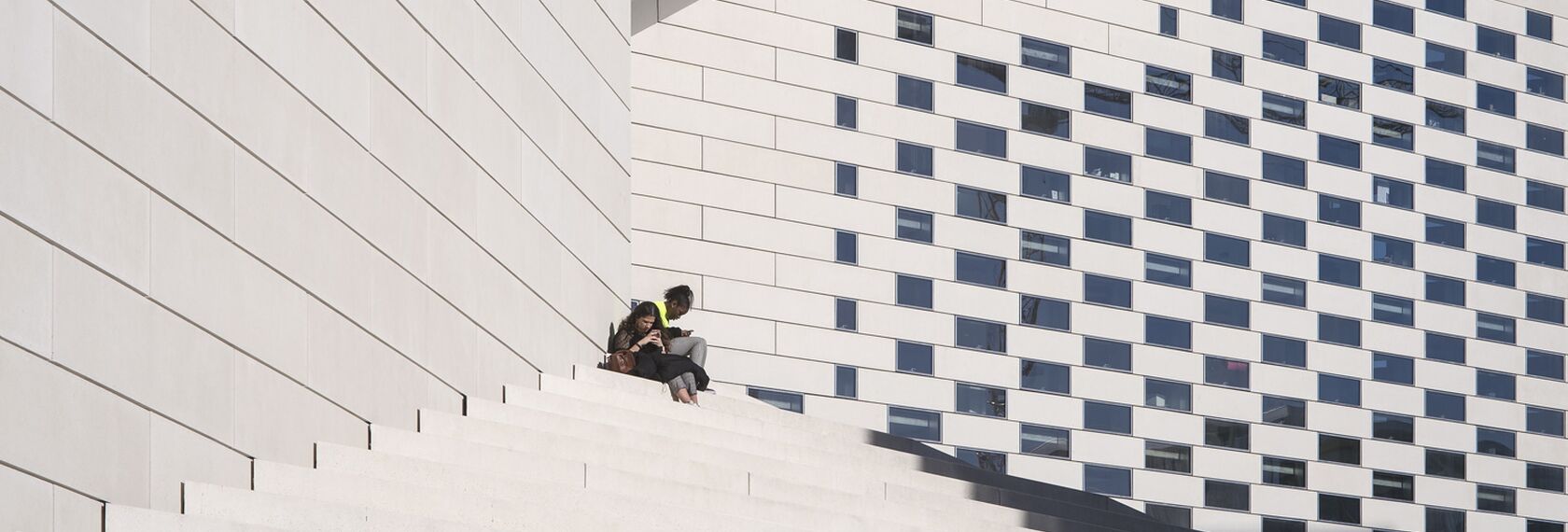 People sitting on the steps of LA MÉCA museum, which features Reynaers Aluminium windows.