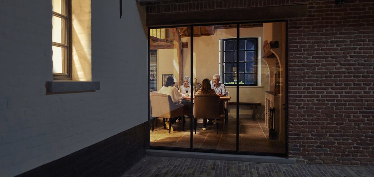 Family sitting at table behind large window at night.