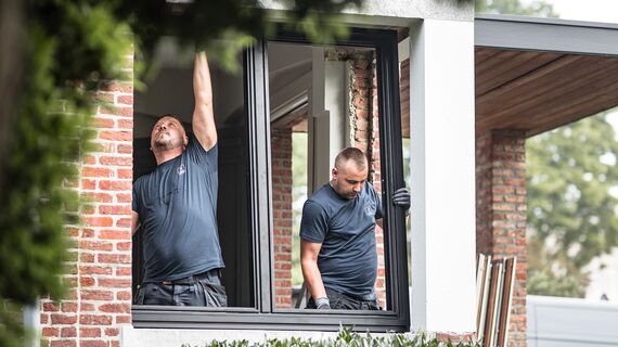 Két szerelő új alumíniumprofilokat helyez el a felújított otthonban.